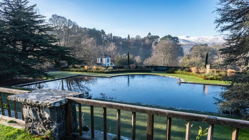 Looking out across the Terraces at Bodnant Garden, with the Pin Mill and snowy mountains in the background
